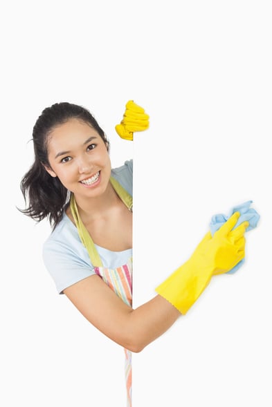 Smiling woman in apron and rubber gloves cleaning white surface