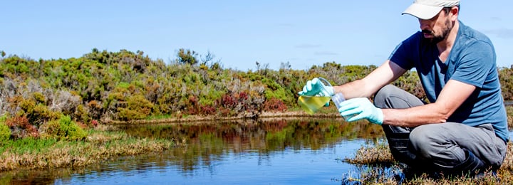 Man-testing-environmental-water-quality-near-body-of-water